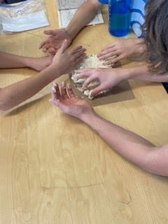 Students hands working on project together at micro school.