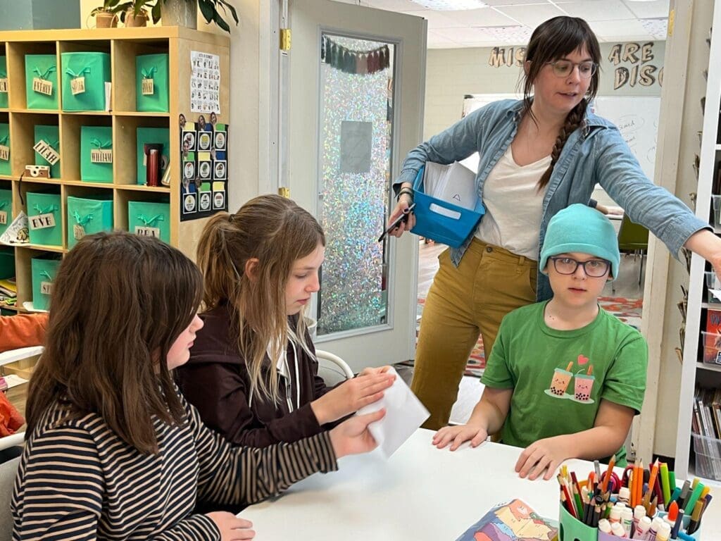 Teacher interacts with students at table at micro school with small classes.
