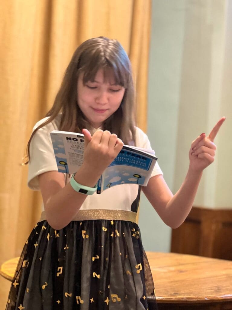 Middle school student raises finger during theater performance at project based school.