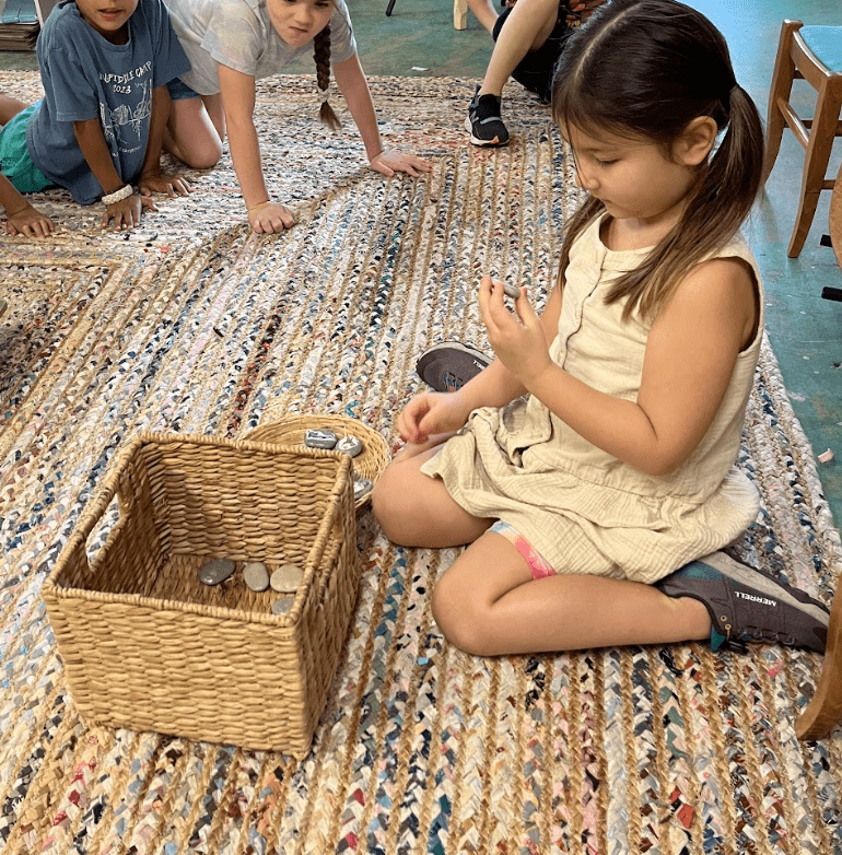 Kindergarten girl chooses object out of basket at private school in Austin.