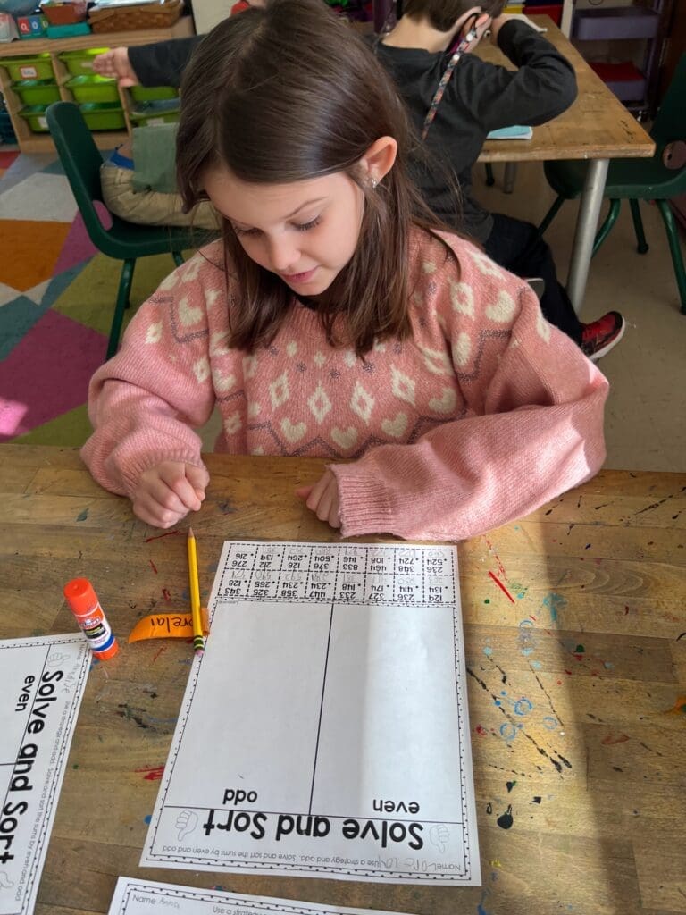 Elementary student works on paper at table at school with small classes.
