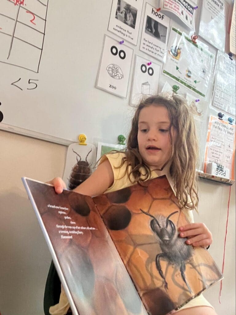 Elementary student reads to class at school with small classes.