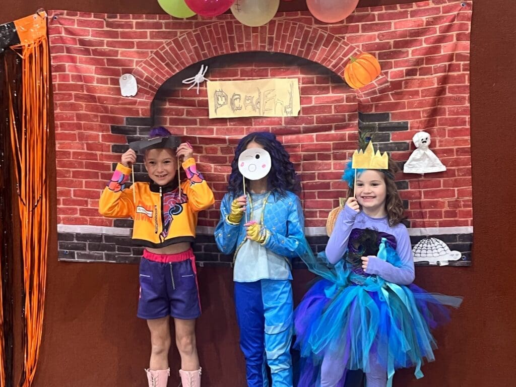 Three elementary students pose for halloween picture at school with small class sizes.